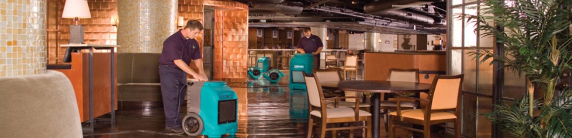 two techs using machines to clean up flooded space